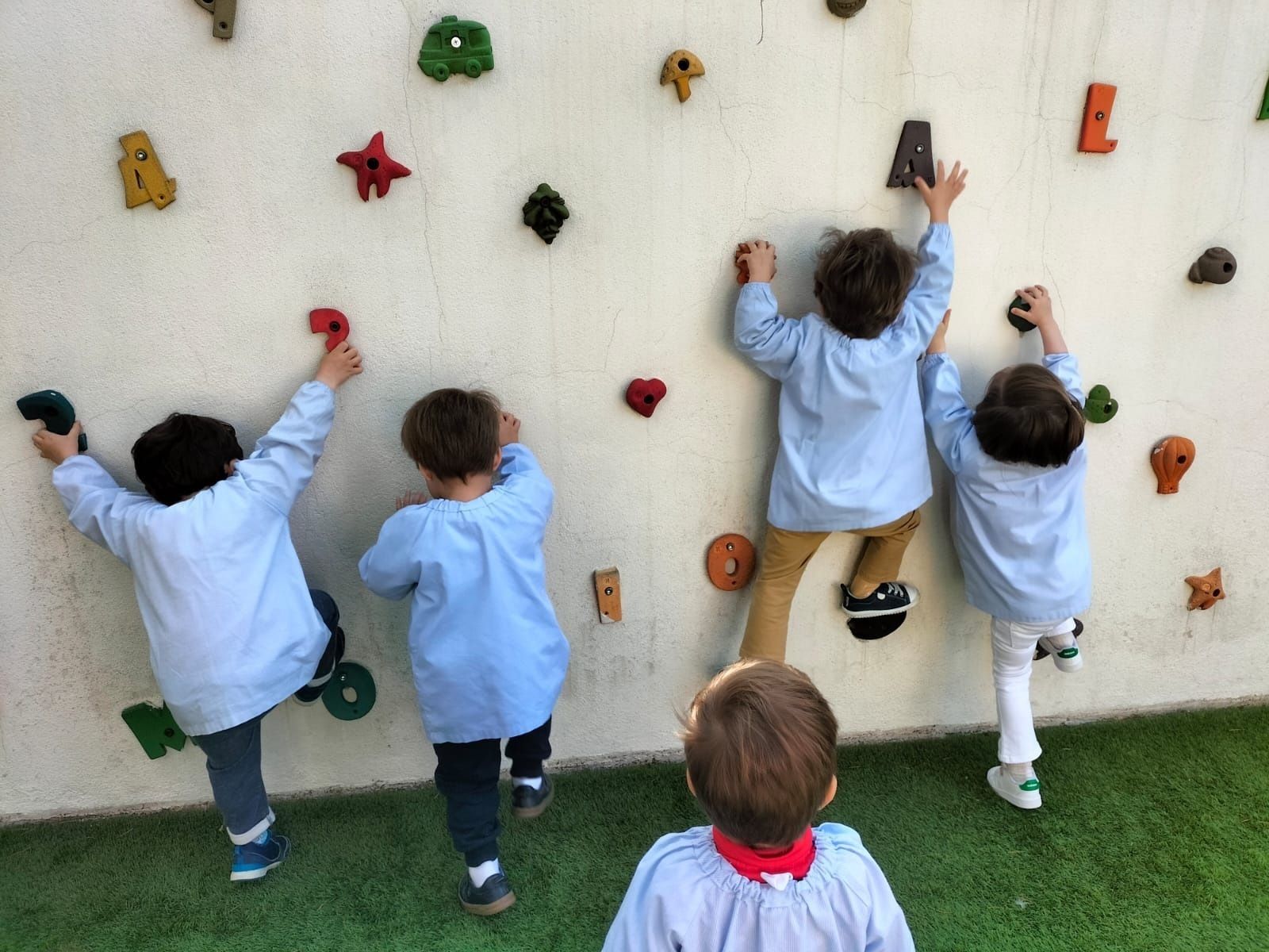 Niños de corta edad juegan a trepar por una pared