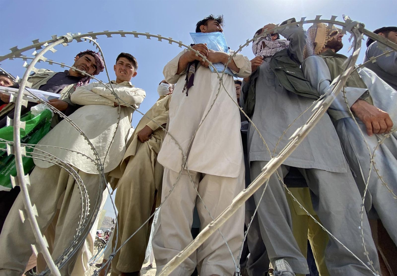 Un grupo de afganos esperan en las afueras del aeropuerto de Kabul para intentar abandonar el país