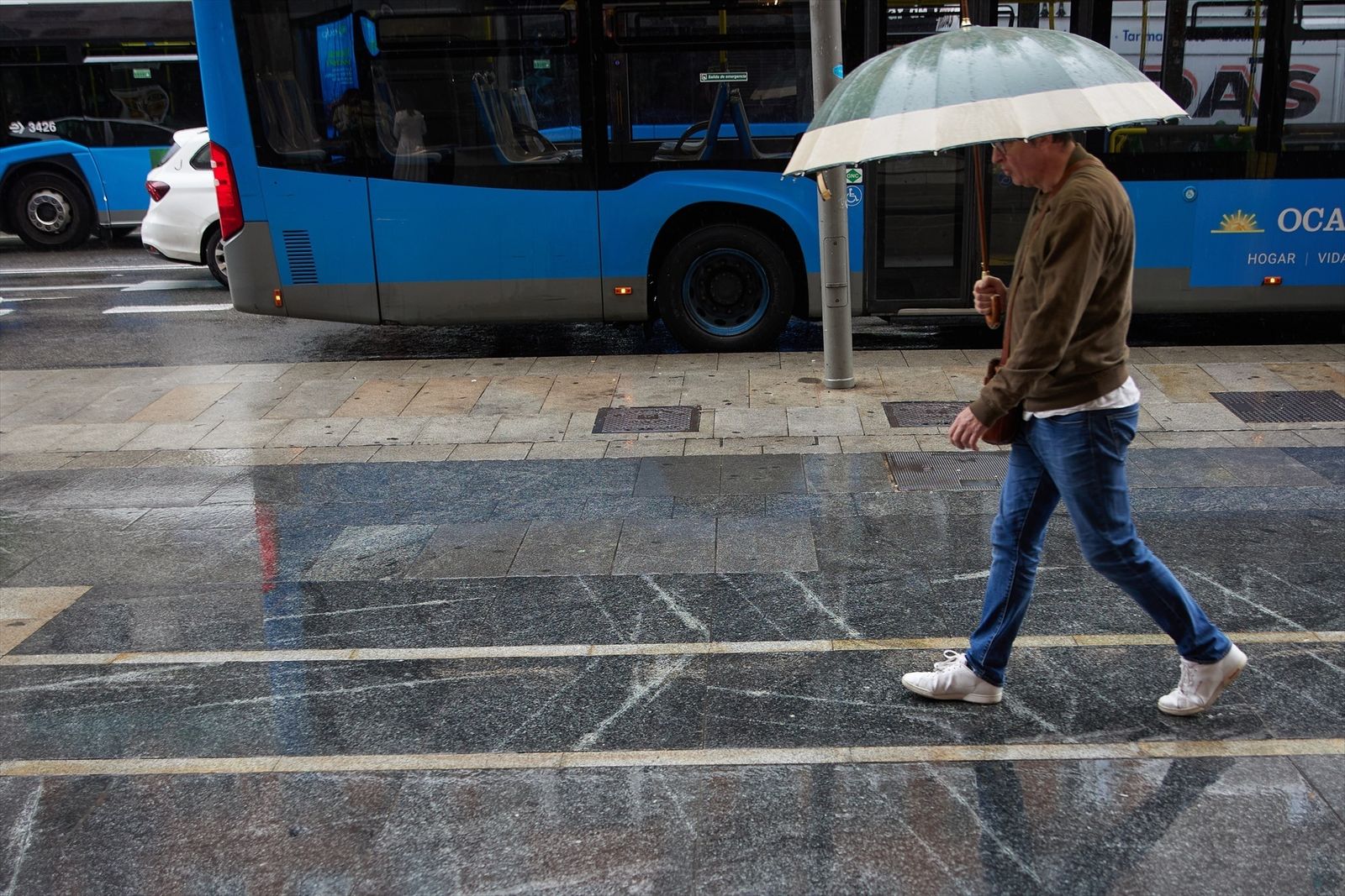 Un hombre con paraguas camina bajo la lluvia por el centro de Madrid