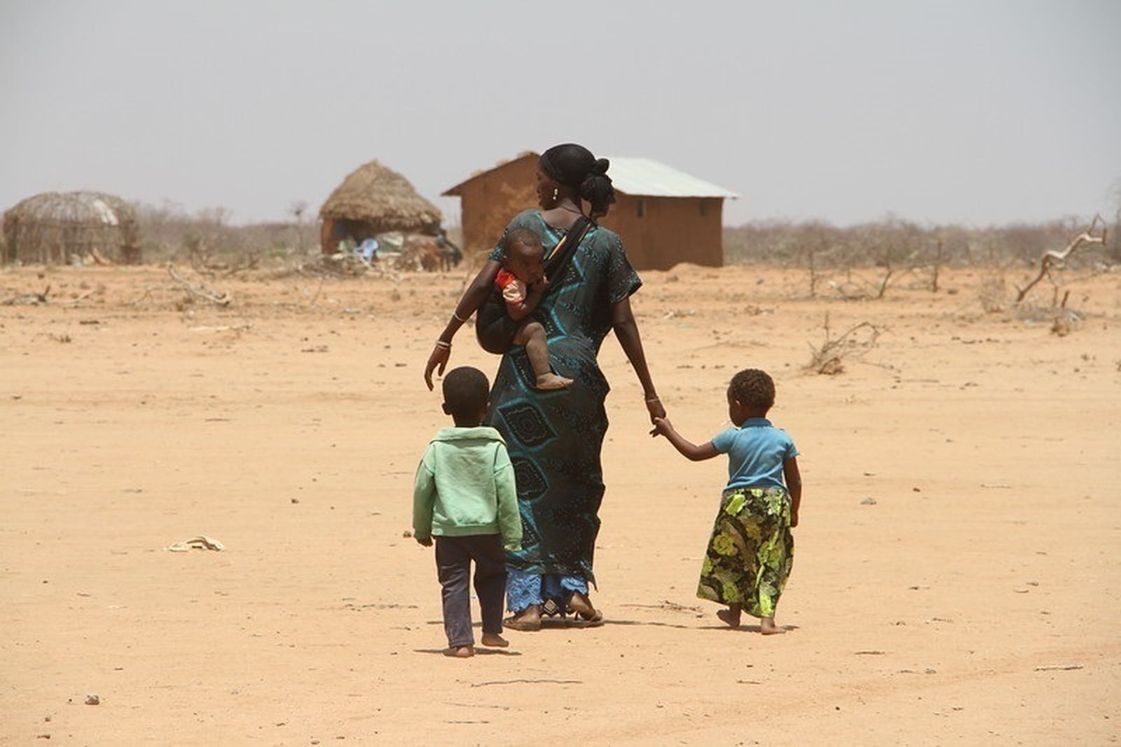 Mujer caminando con sus hijos cerca de una aldea