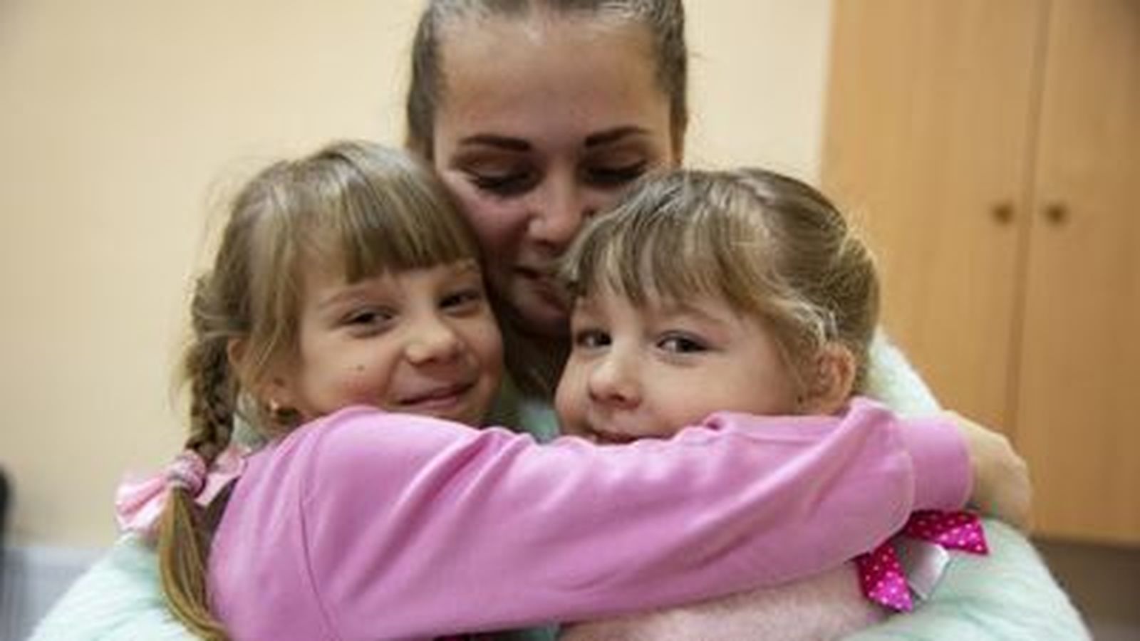 Una madre abraza a sus hijas