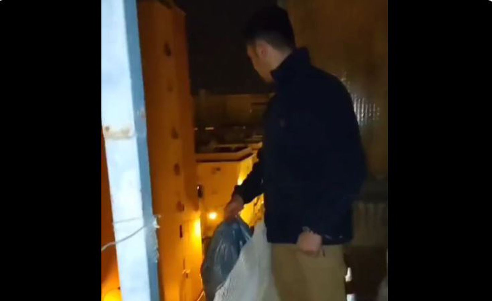 Joven lanzando una bolsa de basura desde su terraza