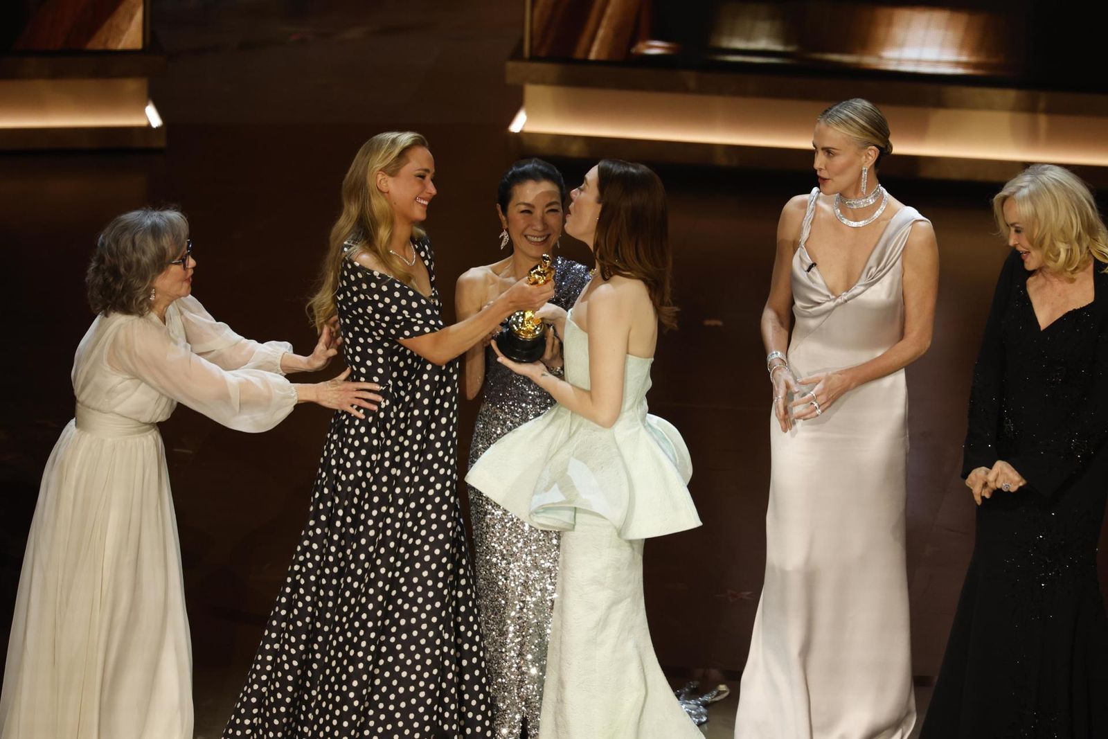 Emma Stone (3-R) is handed the Oscar for Best Actress In A Leading Role from Jennifer Lawrence (2-L) as Sally Field (L) Michelle Yeoh (3-L) Charlize Theron (2-R) and Jessica Lange (R)