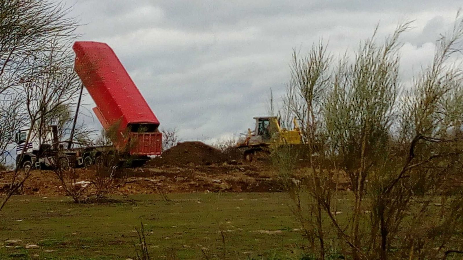 Un camión vuelca su carga junto a una escombrera, cerca de la A-5