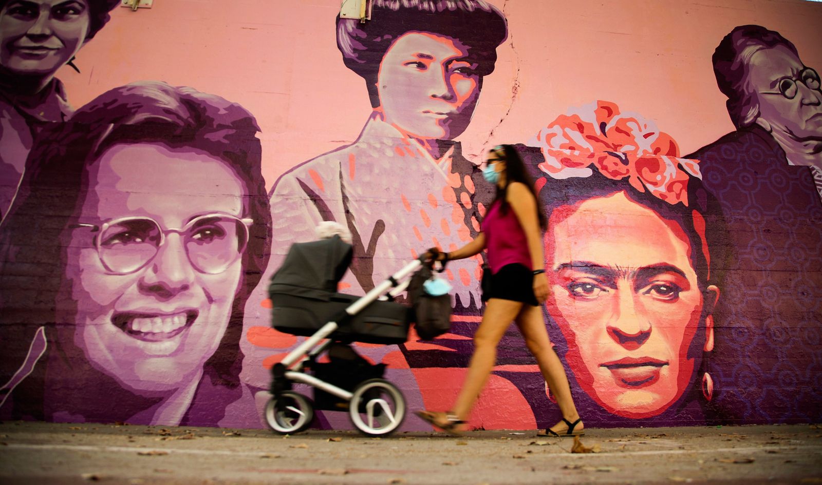 Una mujer camina junto al mural de las mujeres del barrio de Ciudad Lineal en Madrid